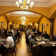 Gente disfrutando de una cena en un elegante salón con arcos y lámparas doradas. Un ambiente perfecto para comer en Olite.