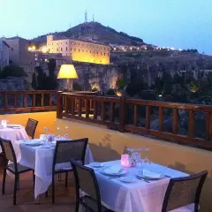Mesas puestas en terraza con vistas a la ciudad iluminada. Un lugar ideal donde comer en Cuenca al anochecer.