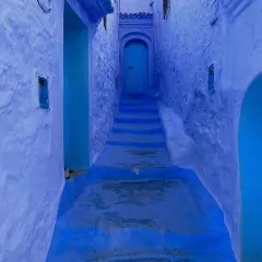 Callejón azul en Chefchaouen, con escalones que suben hacia una puerta. A pesar de su belleza, Chefchaouen es peligroso para los que se pierden en sus laberintos.