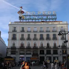 Edificio emblemático en la Puerta del Sol, Madrid. Ideal para saber qué ver en Madrid en un día, con el cartel de Tío Pepe y gente paseando.