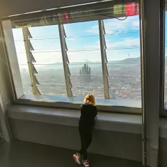 Niña contempla la Sagrada Familia desde el mirador Torre Glòries. El sol ilumina la ciudad.