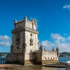 Torre de Belém, un sitio histórico perfecto para un free tour Lisboa. El cielo azul y el agua reflejan su belleza.