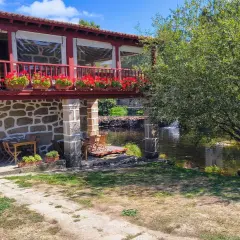 Casa rural con balcón florido y río. Un lugar idílico para descubrir qué ver en Allariz y disfrutar de la naturaleza.