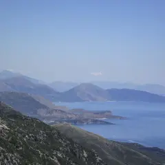 Paisaje montañoso con el mar azul al fondo, ideal para viajar a Albania y disfrutar de vistas espectaculares.