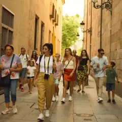 Un grupo disfruta de un free tour en Salamanca, guiado por una mujer con un micrófono, mientras pasean por una calle estrecha y empedrada.