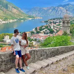 Pareja disfrutando de la vista panorámica de la bahía y la ciudad de Kotor, un destino ideal para viajar a Montenegro.