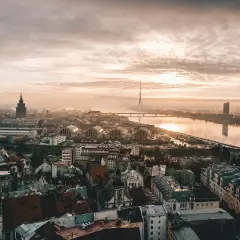 Vista aérea de Riga al amanecer, perfecta para planear tu viajar a Letonia. El río Daugava refleja el cielo nublado y la torre de televisión.