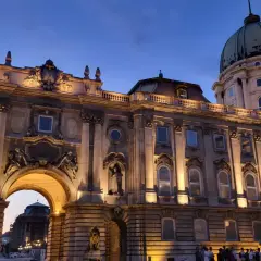 Palacio de Buda iluminado al atardecer, ideal para **free tours Budapest**. Una joya arquitectónica con cúpula verde y detalles ornamentados.