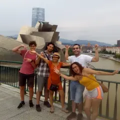 Grupo de amigos disfrutando de un free tour Bilbao, posando con el icónico Museo Guggenheim de fondo.