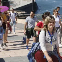 Un grupo de turistas participa en un free tour Gijón, disfrutando del paseo marítimo bajo un sol radiante.