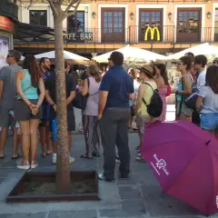 Grupo de turistas esperando un free tour a Toledo. Un paraguas morado con el logo de "Free Tour Toledo" está en primer plano.