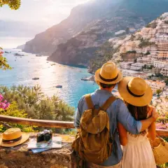 Pareja con sombreros admira la costa italiana. Planear cómo viajar barato es clave para disfrutar de vistas así.