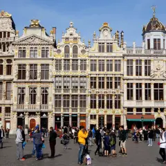 Gente paseando por la Grand Place de Bruselas, admirando la arquitectura dorada. Un lugar perfecto para viajar a Bruselas y capturar recuerdos.