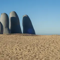 Escultura de una mano emergiendo de la arena en Punta del Este. Un imperdible que ver en Uruguay.