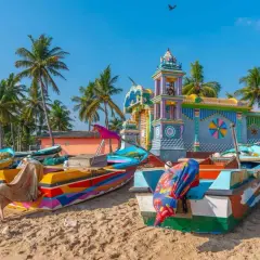 Barcas coloridas en la playa de Sri Lanka, con un templo vibrante al fondo. Es seguro viajar a Sri Lanka y disfrutar de su belleza.