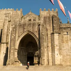 Impresionante Catedral de Tui, un lugar imprescindible que ver en Tui. Fachada de piedra con arco gótico y una persona en las escaleras.