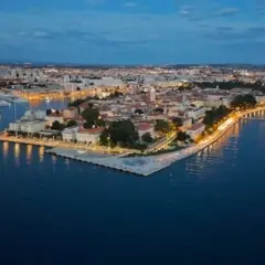 Vista aérea de Zadar al anochecer. La ciudad iluminada se extiende a lo largo de la costa, con el mar Adriático en primer plano. ¡Mucho que ver en Zadar!