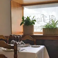 Mesa puesta con copas y plantas en ventana, ideal para saber donde comer en Cáceres.