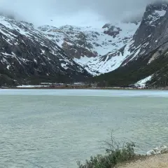 Dos personas admiran un lago helado y montañas nevadas, un paisaje impresionante de lo que ver en Argentina.