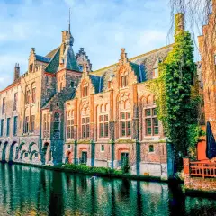 Edificios históricos de ladrillo a lo largo de un canal, reflejando la belleza de Brujas, un viaje inolvidable de Bruselas a Brujas.