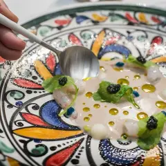 Delicioso plato de mariscos con caviar y hojas verdes, servido en una vajilla colorida. Una excelente opción para saber donde comer en Córdoba.