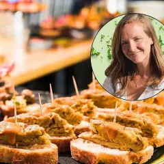 Una mujer sonríe mientras disfruta de deliciosos pintxos, una experiencia culinaria para comer en San Sebastián.