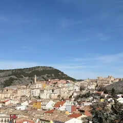 Vista panorámica de Cuenca, con sus casas de colores y tejados anaranjados, asentadas en una ladera rocosa bajo un cielo azul. Ideal para saber qué ver en Cuenca en un día.