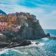 Pueblo costero italiano con casas coloridas en acantilados. Ideal para excursiones desde Milán.