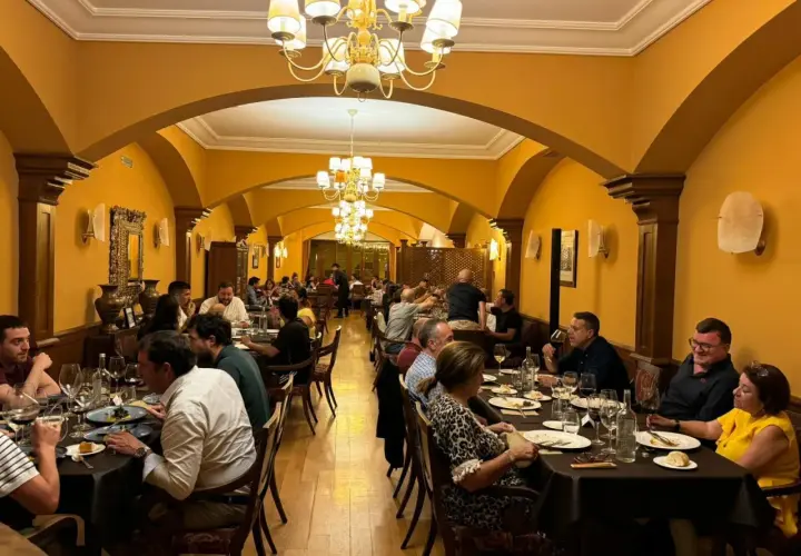 Gente disfrutando de una cena en un elegante salón con arcos y lámparas doradas. Un ambiente perfecto para comer en Olite.