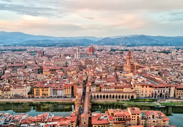 Vista panorámica de Florencia al atardecer, con la cúpula del Duomo y el Ponte Vecchio. Ideal para un **free tour Florencia**.