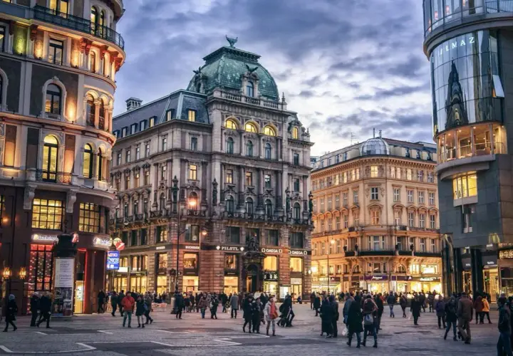 Gente paseando por una plaza en Viena, con edificios históricos y modernos. Ideal para un **free tour Viena**.
