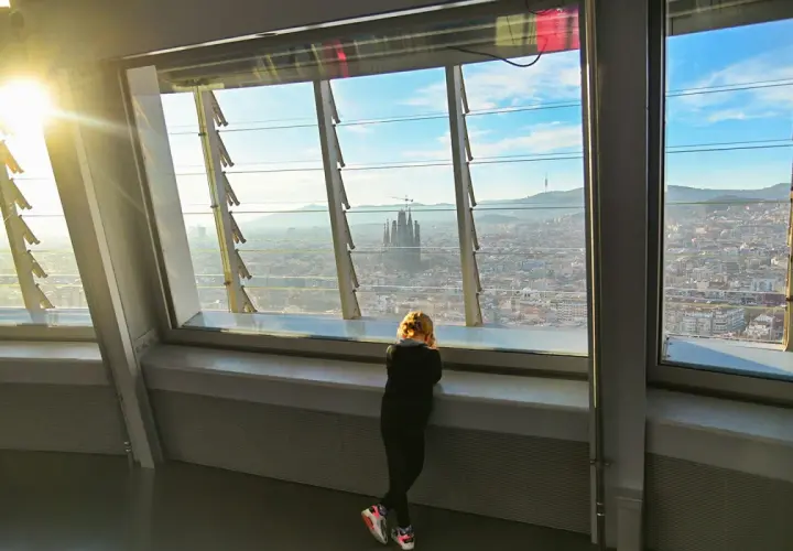 Niña contempla la Sagrada Familia desde el mirador Torre Glòries. El sol ilumina la ciudad.