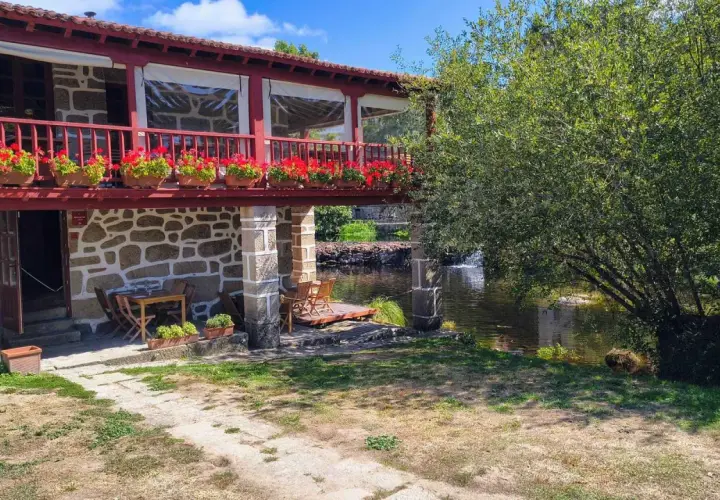 Casa rural con balcón florido y río. Un lugar idílico para descubrir qué ver en Allariz y disfrutar de la naturaleza.