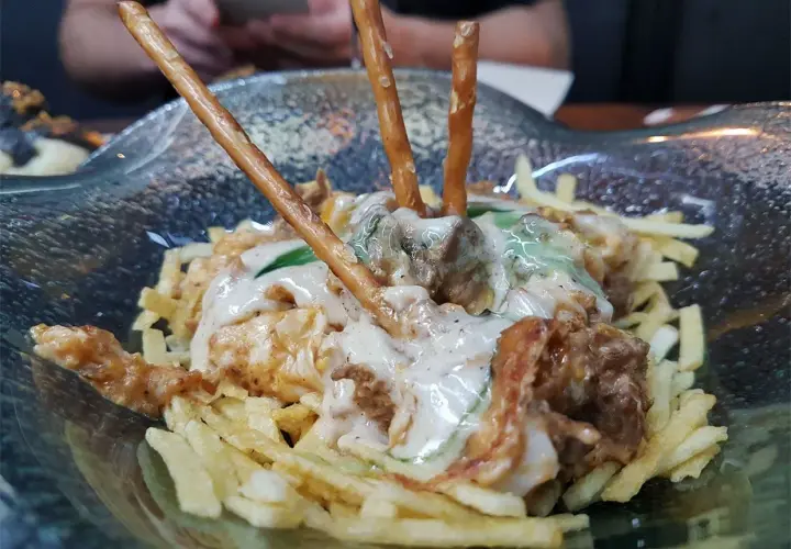 Un plato con patatas fritas, carne y palitos de pretzel. ¡Una idea de dónde comer en Cádiz!