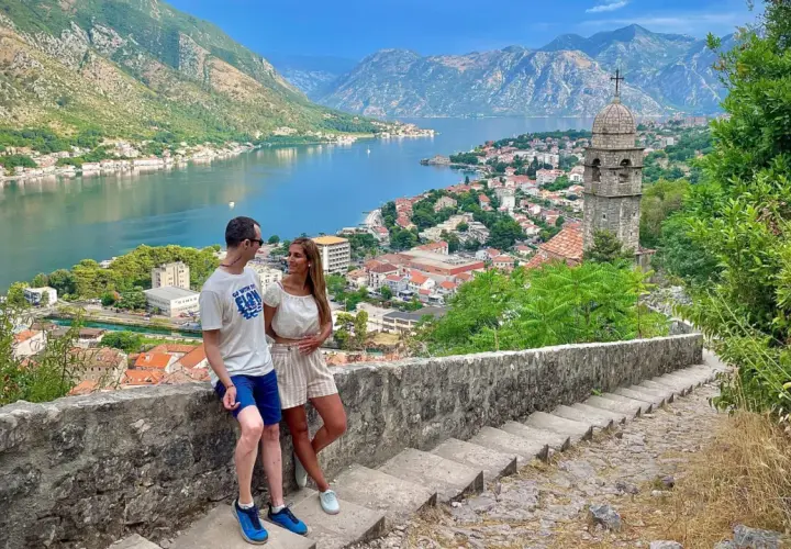 Pareja disfrutando de la vista panorámica de la bahía y la ciudad de Kotor, un destino ideal para viajar a Montenegro.