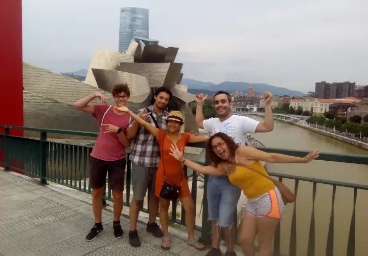 Grupo de amigos disfrutando de un free tour Bilbao, posando con el icónico Museo Guggenheim de fondo.