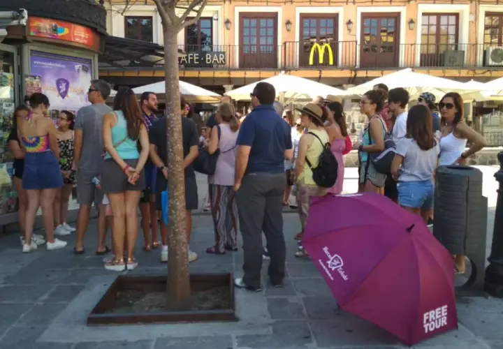 Grupo de turistas esperando un free tour a Toledo. Un paraguas morado con el logo de "Free Tour Toledo" está en primer plano.