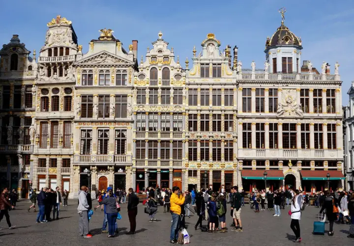Gente paseando por la Grand Place de Bruselas, admirando la arquitectura dorada. Un lugar perfecto para viajar a Bruselas y capturar recuerdos.