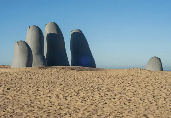 Escultura de una mano emergiendo de la arena en Punta del Este. Un imperdible que ver en Uruguay.