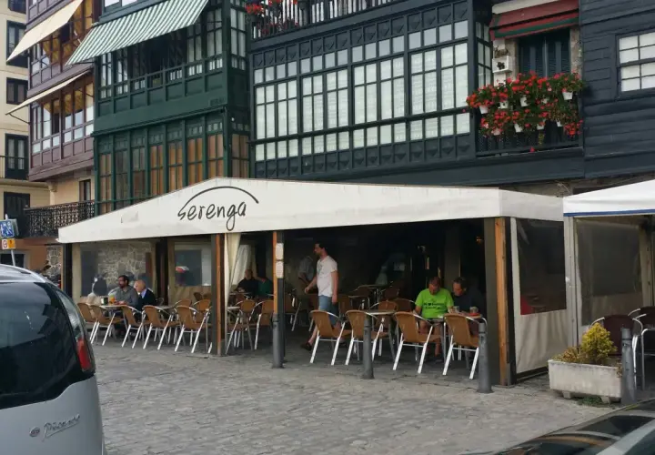 Gente disfrutando de un día soleado para comer en Lekeitio, sentados en las mesas de un restaurante con toldo blanco.