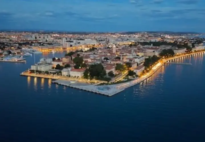Vista aérea de Zadar al anochecer. La ciudad iluminada se extiende a lo largo de la costa, con el mar Adriático en primer plano. ¡Mucho que ver en Zadar!