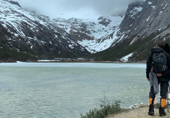 Dos personas admiran un lago helado y montañas nevadas, un paisaje impresionante de lo que ver en Argentina.