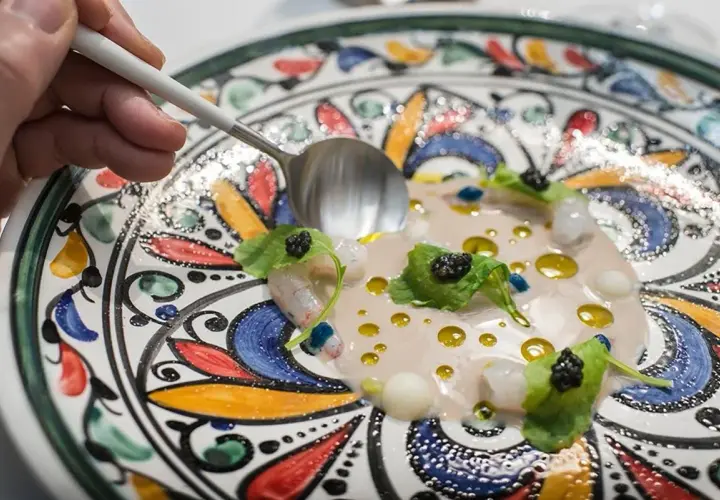 Delicioso plato de mariscos con caviar y hojas verdes, servido en una vajilla colorida. Una excelente opción para saber donde comer en Córdoba.