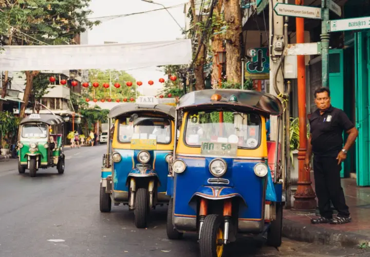 Tuk-tuks coloridos en una calle de Bangkok, perfectos para explorar la ciudad. ¡La mejor época para viajar a Tailandia es ahora!