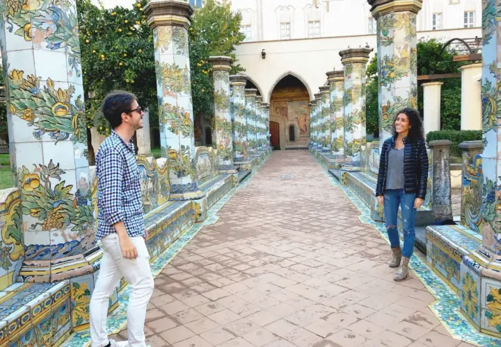 Pareja admira la cerámica de mayólica en un claustro, ideal para ver en Nápoles en 1 día.