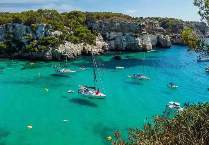 Calas turquesas y veleros anclados, ideal para saber qué ver en Menorca en 3 días. Disfruta de un día perfecto en este paraíso.