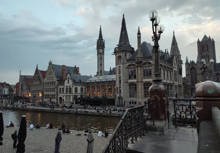 Gante, Bélgica: edificios históricos junto al río, gente sentada en la orilla. Un lugar ideal que ver en Bélgica.