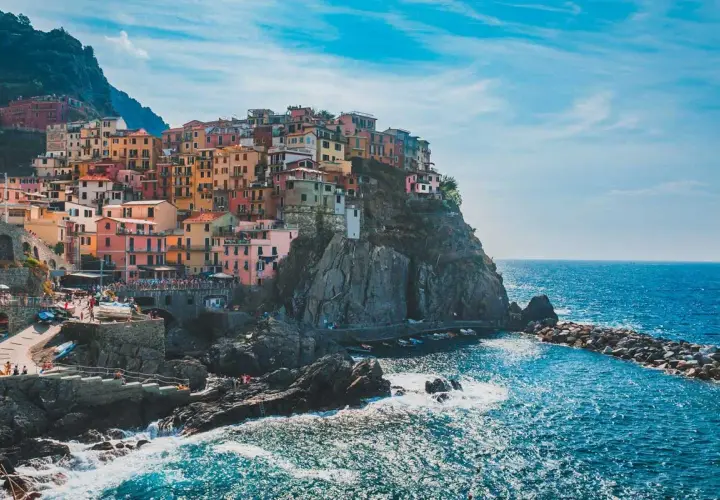Pueblo costero italiano con casas coloridas en acantilados. Ideal para excursiones desde Milán.