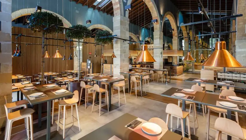Mesas listas para comer en el puerto de Santa María. Ambiente moderno con lámparas de cobre y detalles de madera.