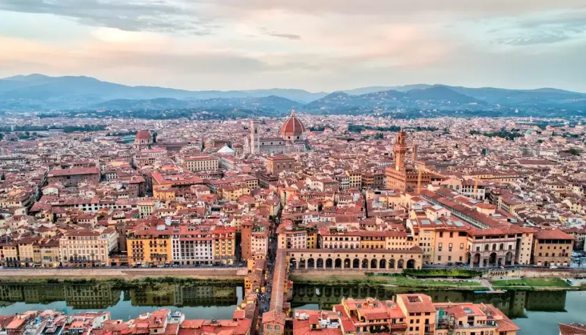 Vista panorámica de Florencia al atardecer, con la cúpula del Duomo y el Ponte Vecchio. Ideal para un **free tour Florencia**.
